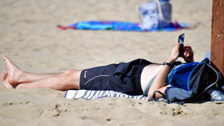 La chaleur est arrivée fort ! Assurez-vous que votre smartphone ne surchauffe pas 4 Homme sur la plage avec smartphone